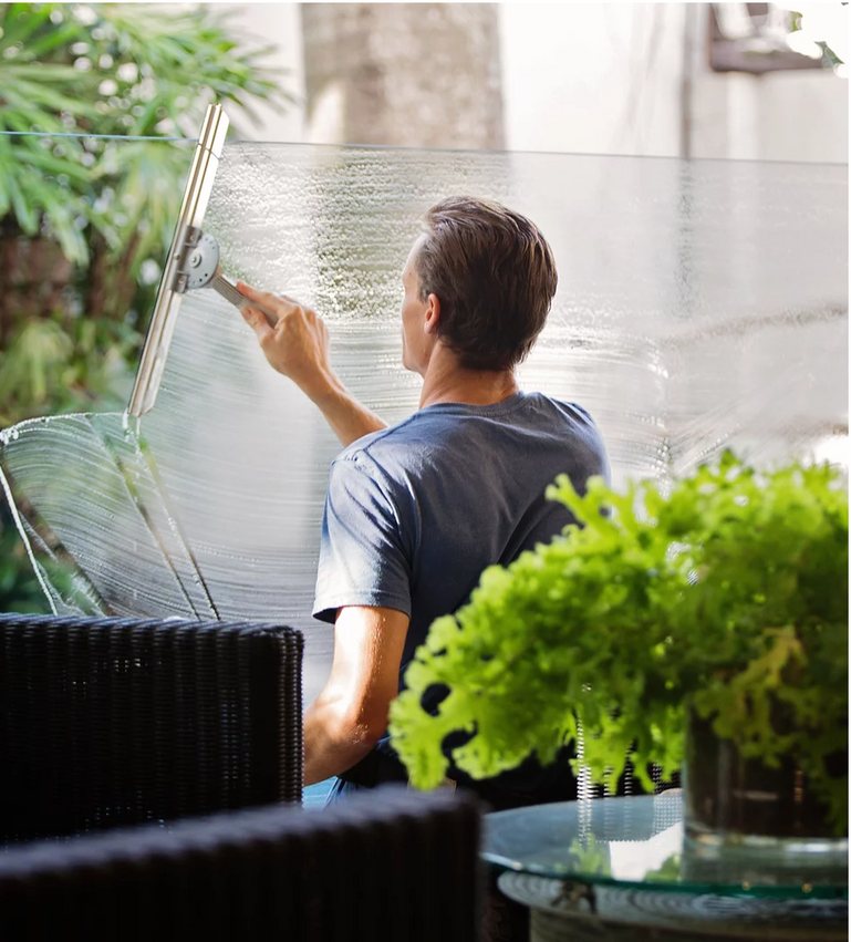 A Prairie Building Maintenance cleaner washing glass at a Manitoba workplace